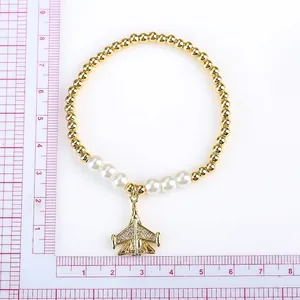 Elastic beaded bracelet featuring a gold airplane pendant with pave diamonds and white pearls
