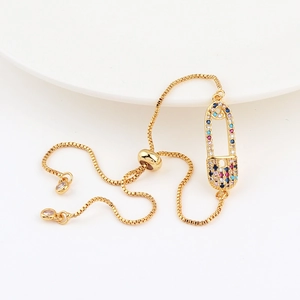 Macro shot of gold safety pin charm with colorful zircon stones on adjustable bracelet