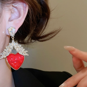 Gros plan d'une boucle d'oreille cœur rouge en résine avec des cristaux étincelants