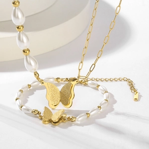 Elegantes Set aus goldener Schmetterlingskette und Perlenarmband auf Marmor