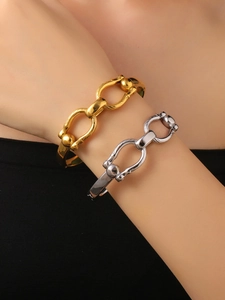Close-up of stacked gold and silver chain bracelets with gauge link design on arm