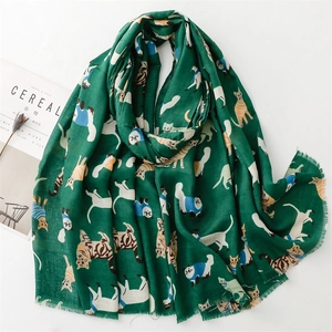 Detailed flat lay of dark green scarf with cartoon cat prints and frayed edge details