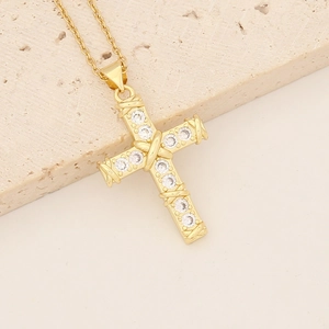 Macro view of gold-plated copper cross necklace with zircon stones on stone background