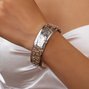 Close-up of silver wide bangle with intricate embossed floral scroll patterns