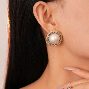Close-up of French vintage style round pearl earrings with woven metal chain texture