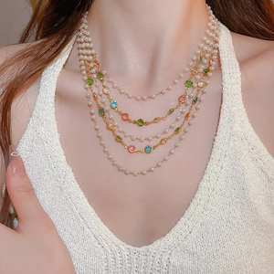 Detail of layered pearl necklace with colorful gemstones on a woman's neck