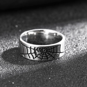 Macro detail of silver stainless steel ring with black spider web pattern engraving
