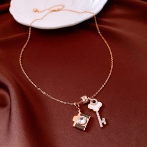 Macro detail of rose gold key pendant with zircon and enamel camera charm on chain