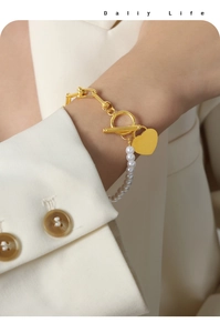 Detail of gold heart pendant on mixed pearl and metal chain bracelet with OT clasp