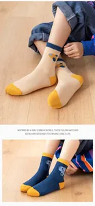 Detail of cotton kids socks with blue car and dinosaur patterns on light wooden floor