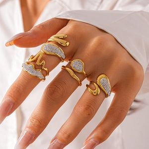 Close-up of golden wavy leaf rings set with sparkling crystals on a woman's fingers