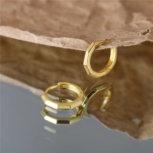 Macro view of gold S925 sterling silver octagonal hoop earrings with a clear reflection