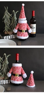 Detail of knitted Santa Claus wine bottle cover and hat with plush trim and gold buckle