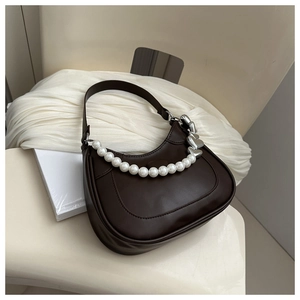 Detail of dark chocolate hobo bag with large pearls and silver heart metallic charm