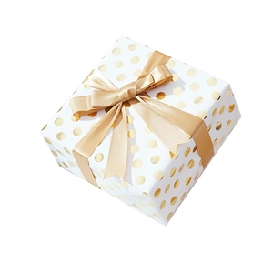 Detail of white gift box with gold foil polka dots and a champagne satin bow decoration