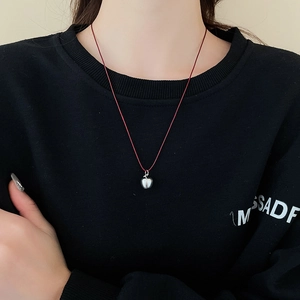 Korean style silver apple pendant necklace with adjustable red cord on black sweater