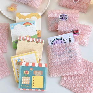 Pink heart-shaped bubble mailers and cute Korean style stationery on a white surface