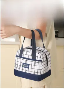 Detail of reinforced handles and navy plaid pattern on the insulated lunch bag