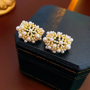 Dettaglio macro di orecchini vintage con perle su un cofanetto in pelle blu di lusso