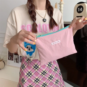 Macro detail of a pink macaron-colored makeup bag with a blue zipper and green puller