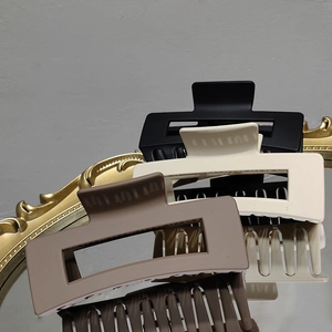Detailed view of large matte hair claws in black, beige, and brown on a vintage mirror