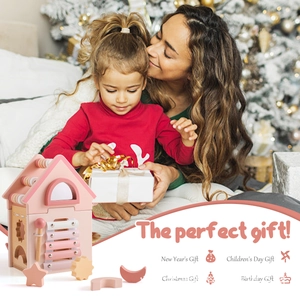 Pink wooden busy house toy with xylophone and shape sorter shown in a warm holiday setting