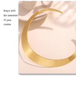 Macro detail of high-polish gold crescent neck collar on a textured cream surface