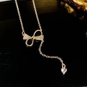 Détail du collier doré avec nœud en zircone et pendentif en pierre de cœur rose
