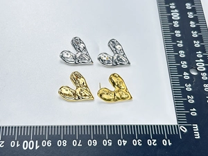 Détail macro de boucles d'oreilles cœur fondu en or et argent avec texture martelée