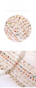 Macro detail of gold-plated chain links with enamel flowers and colorful charms