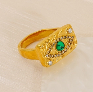 Détail d'une bague œil maléfique dorée avec malachite et accents de cristaux blancs