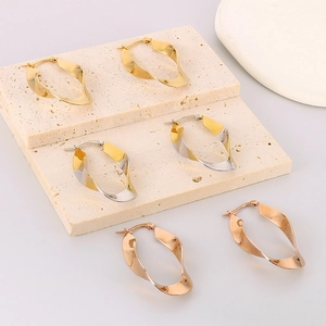 Detailed macro view of twisted U-shaped earrings in gold, silver, and rose gold finishes