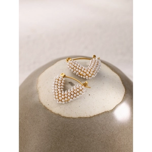 Detailed macro shot of a heart-shaped gold earring featuring delicate white pearls
