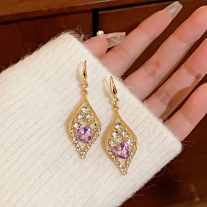 Detail of square gold drop earrings with purple heart gemstone and crystal accents