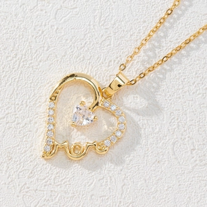 Macro shot of gold heart pendant with white zircon and MOM cutout lettering