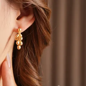 Matte gold clustered bead drop earrings featuring a frosted finish on a fashion model