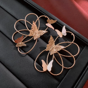 Close-up of rose gold hollow butterfly and twisted wire flower design earrings