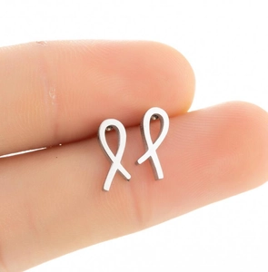 Close-up of minimalist silver ribbon knot stud earrings held to show delicate size