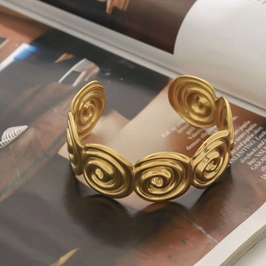 Golden titanium steel wide bangle with textured spiral design and premium metallic luster