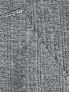 Gros plan détaillé de la texture tricotée et des doubles coutures du cardigan gris