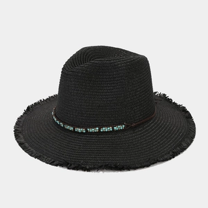 Détail du chapeau de paille noir avec ruban de perles turquoise et bord effiloché