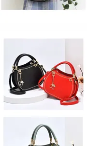 Detailed shot of semi-circular handbags with metal leaf charms in black, red and green