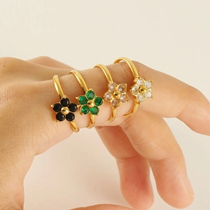 Detail of four floral gold-plated rings with colorful gemstones on a hand
