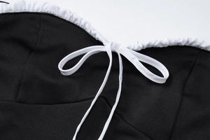 Détail de la bordure à volants blancs et du nœud papillon noir sur la robe d'été ajustée