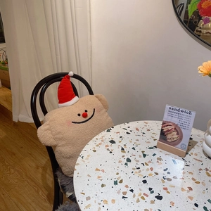 Detail eines Plüsch-Geistkissens mit Weihnachtsmütze auf einem Stuhl im gemütlichen Café