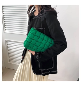 Quilted green padded handbag with puffer square stitching held by a model in a casual outfit
