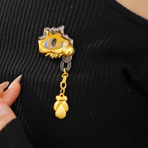 Detailed close-up of a vintage eye brooch with blue iris and golden pendant on black knitwear