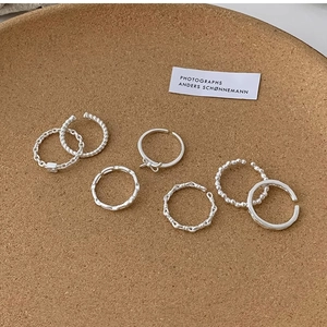 Detailed view of seven silver minimalist rings including twisted and beaded adjustable bands