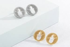Detail of gold and silver stainless steel Hamsa hand stud earrings on display stand