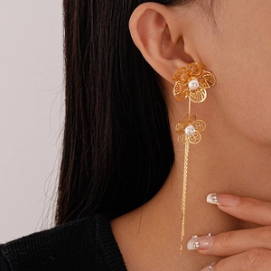 Close-up of elegant gold tassel earrings with hollow flowers and sparkling zircons